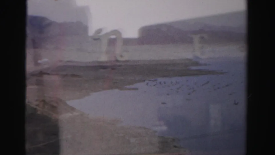 1957 Las Vegas frame with arched decorative forms beside water and distant hills, viewed through a dark interior window division.