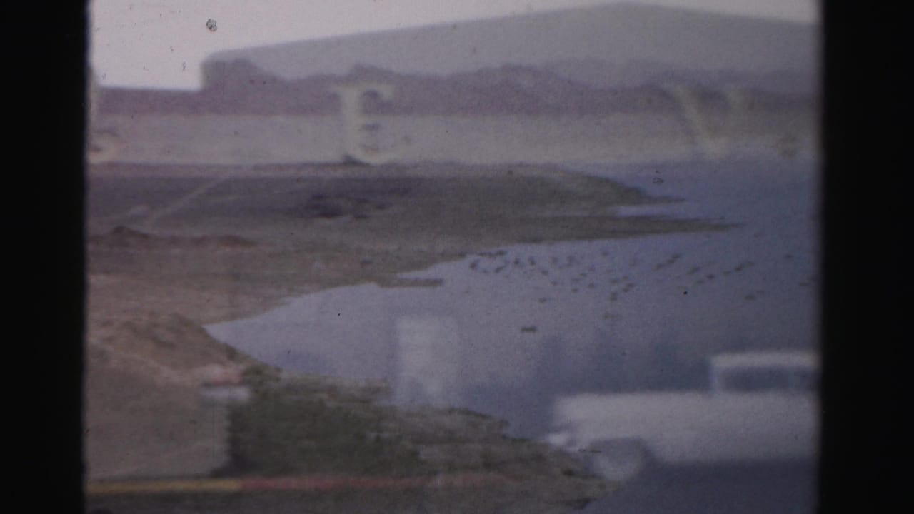 Soft 8mm view of water, desert shoreline, mountains, and partial Royal Nevada lettering.