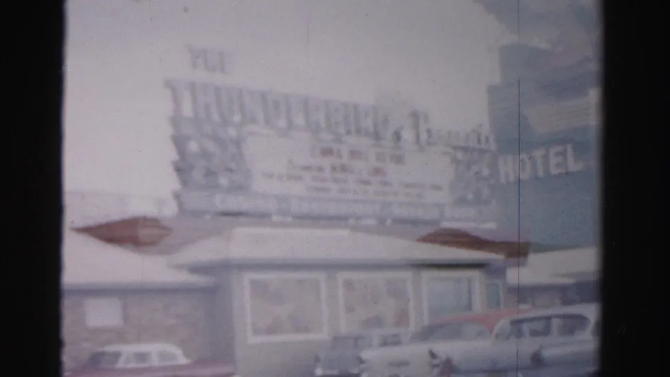 1957 Las Vegas home-movie frame of the Thunderbird Hotel sign, motel-style frontage, and parked cars along the road.