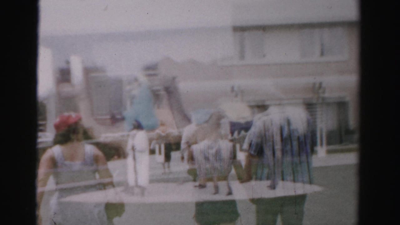 Visitors walk near camel sculptures in front of a beige building.