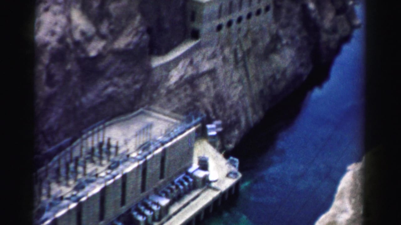 1957 Nevada home-movie frame of Hoover Dam structures set into the canyon, with water visible to the right.