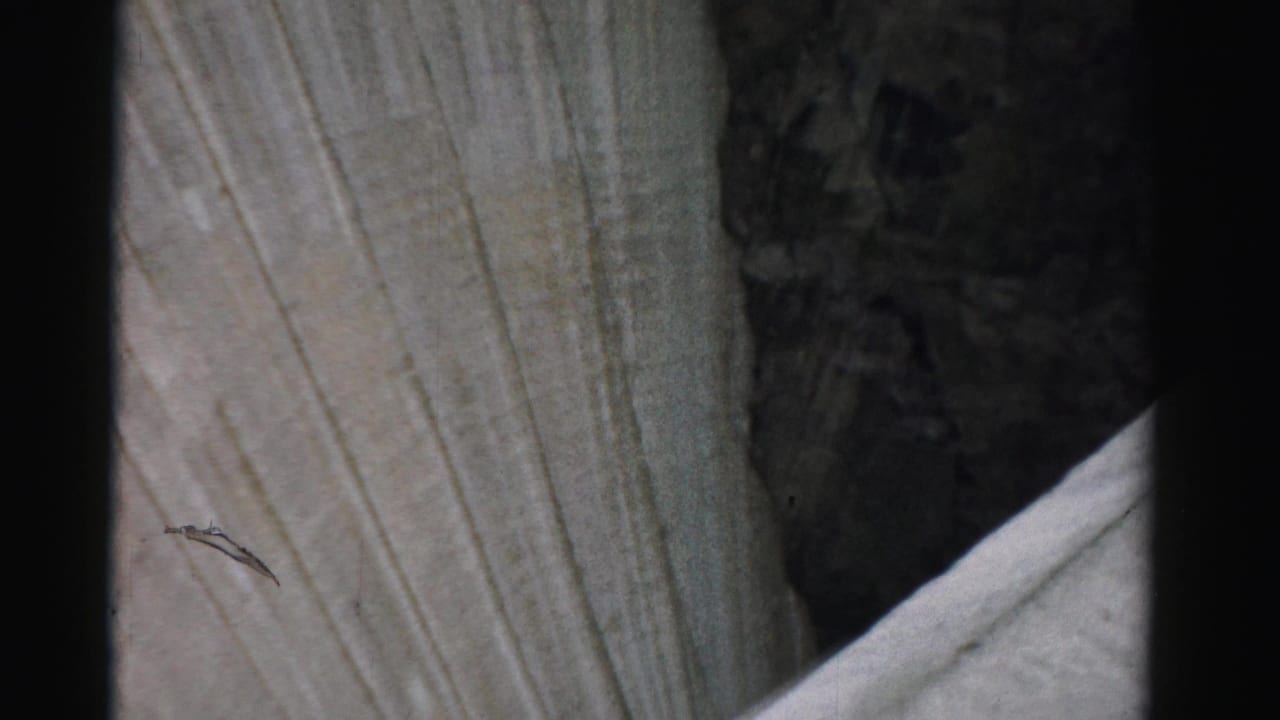 1957 Nevada 8mm frame showing a close high-angle view of concrete surfaces near the edge of a large structure.