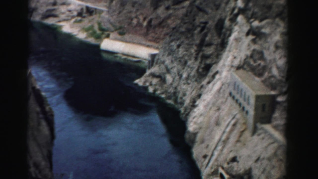 River bend between rocky canyon walls with concrete structures near the cliffs.