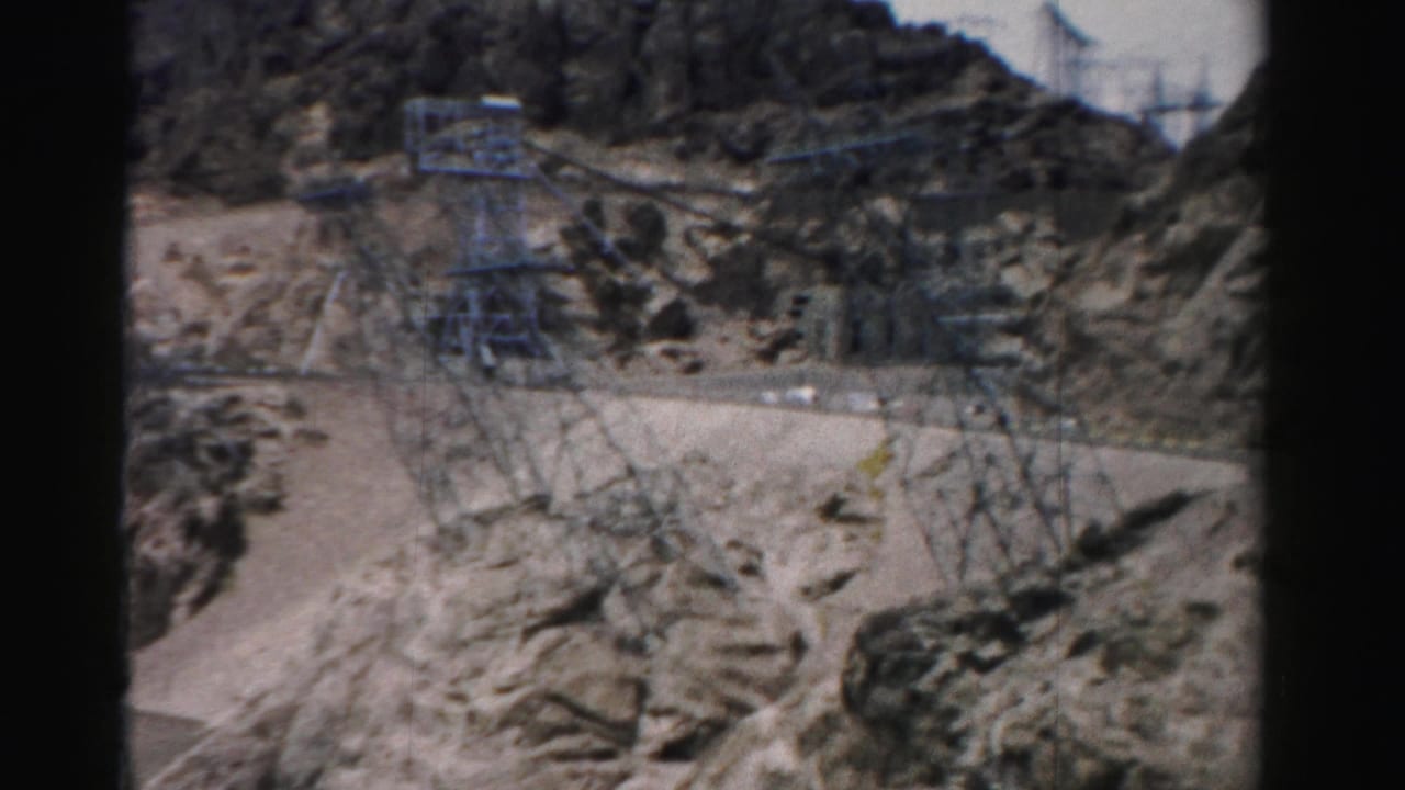 Rocky hillside with road cuts, towers, and dark film-frame borders.