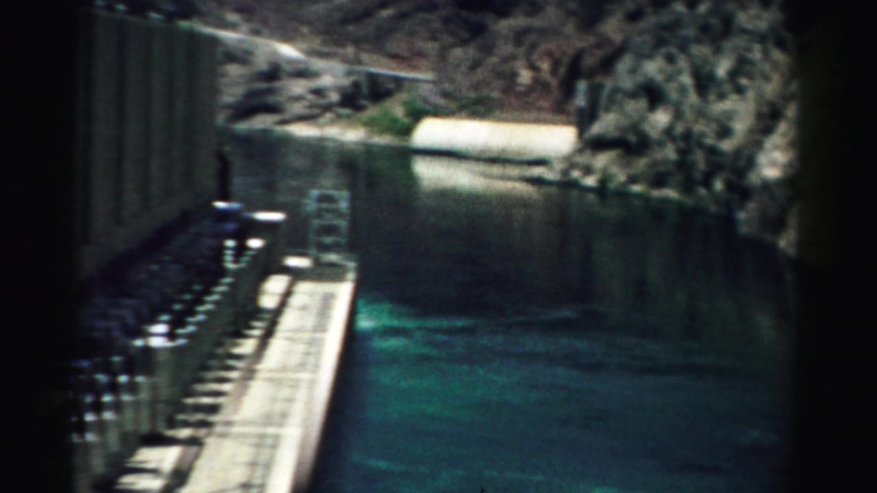 1957 Nevada 8mm view of green water running through a narrow canyon beside concrete dam structures.