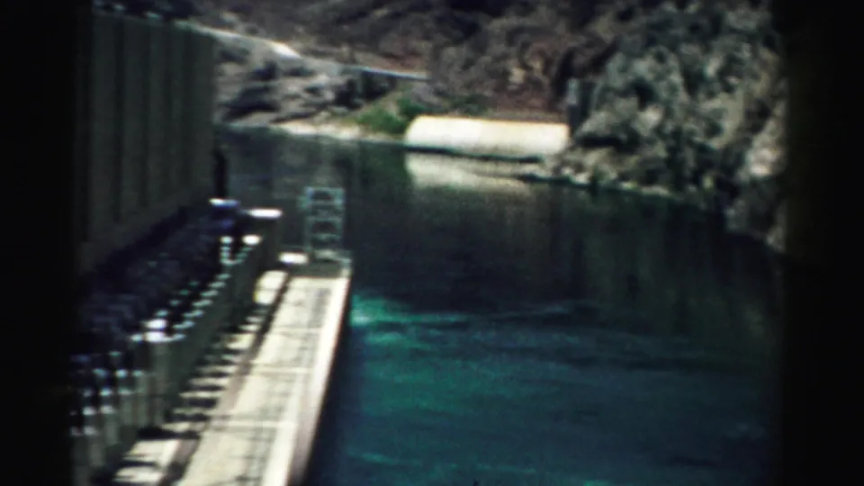 1957 Nevada 8mm view of green water running through a narrow canyon beside concrete dam structures.