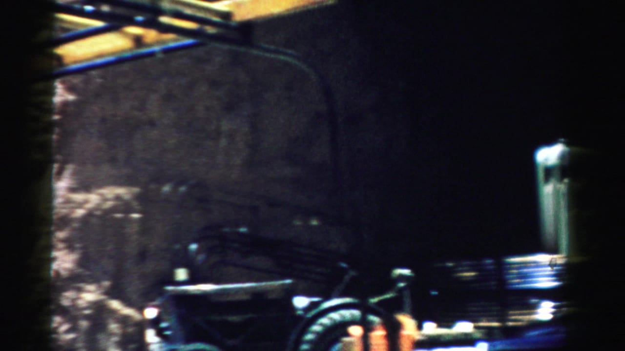 Rocky construction site with a dark work vehicle and equipment near a cliff face.