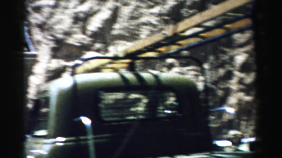 1957 Nevada 8mm frame with motion blur on a dark work vehicle and rocky tunnel-site surroundings.