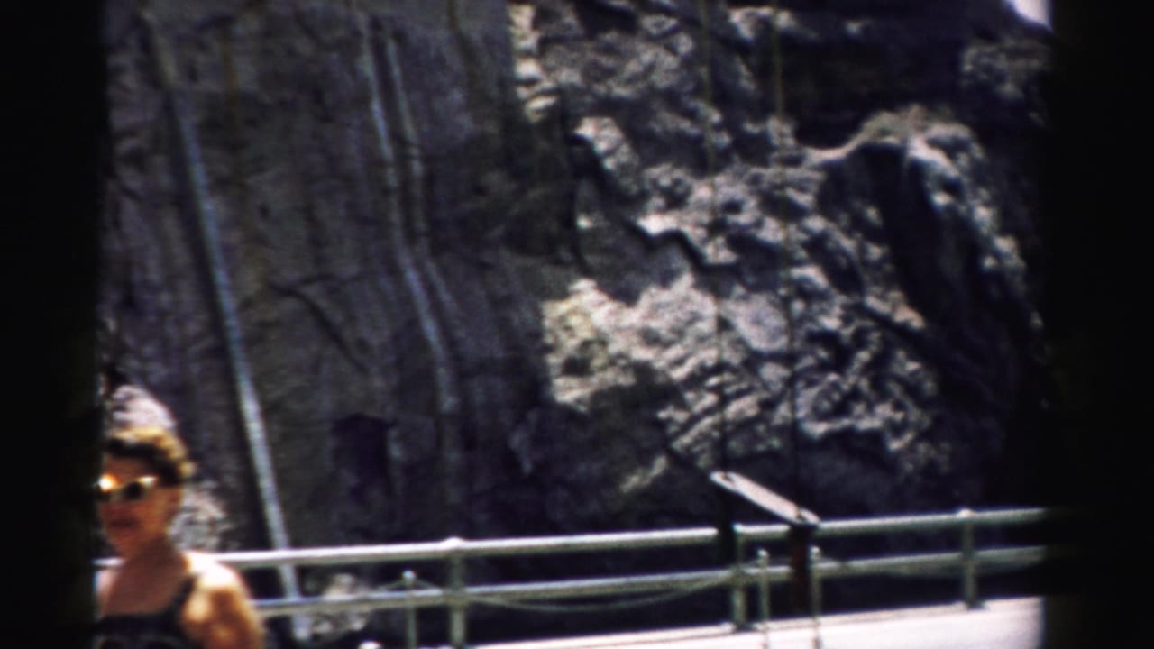 A woman in summer clothing and sunglasses stands near a metal railing in the Nevada mountain setting.
