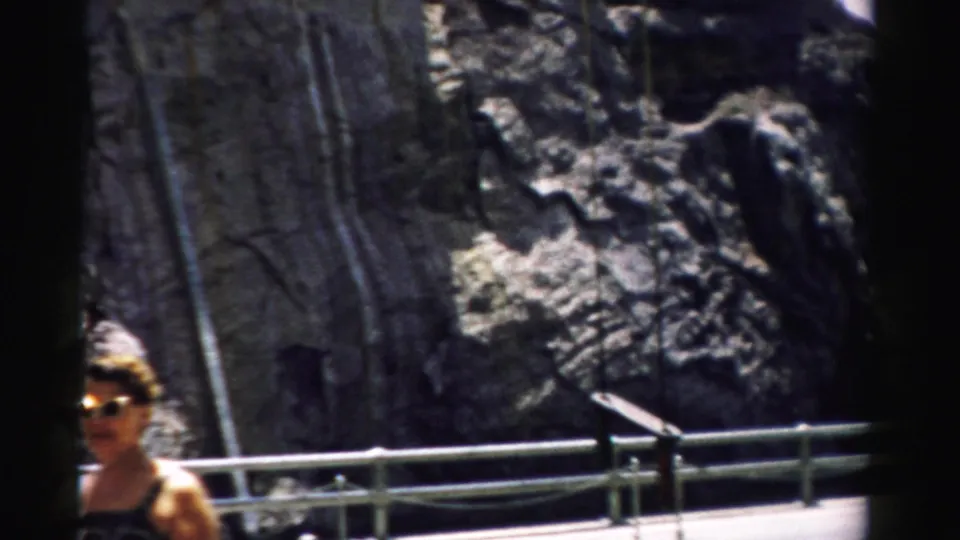A woman in summer clothing and sunglasses stands near a metal railing in the Nevada mountain setting.