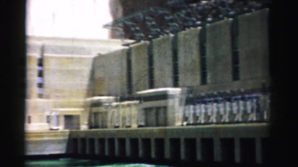 1957 8mm lower view of Hoover Dam in Nevada, showing concrete walls, shadowed base openings, and softened home-movie color.