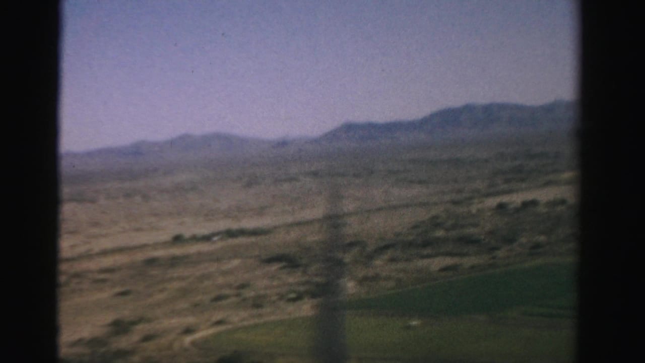 Desert landscape and distant mountains seen through an airplane window.