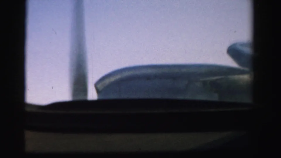 A dark aircraft surface, likely wing or engine housing, is visible below the passenger window in this 1957 home-movie frame.