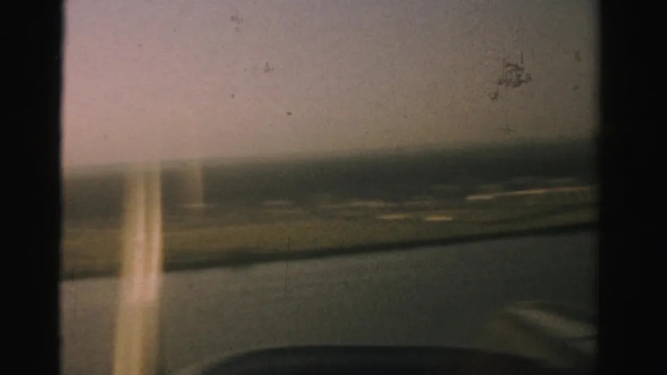 The passenger-window view blurs as the plane lifts over runway markings and open Nevada ground.