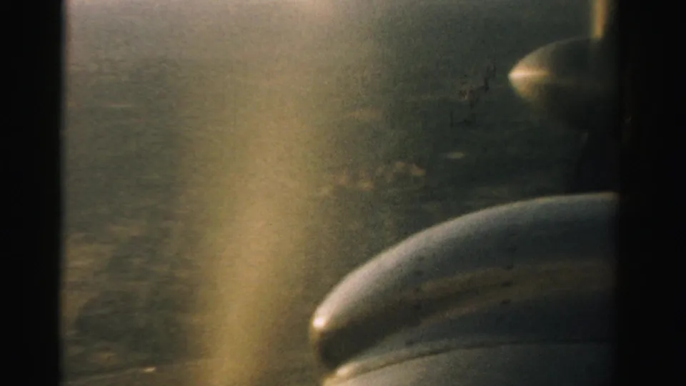 1957 Nevada 8mm frame showing a small aircraft propeller and engine cowling against a hazy aerial landscape.