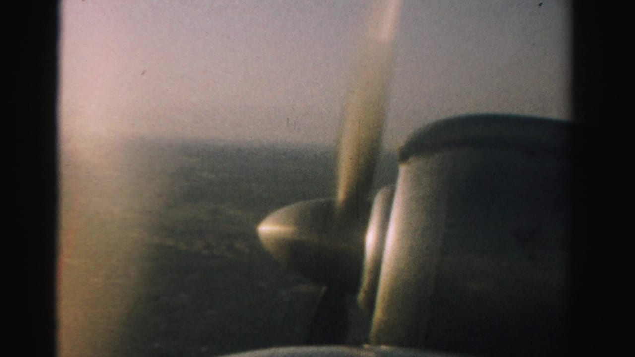 1957 Nevada aerial home-movie view with the small plane propeller and engine visible at the edge of frame.