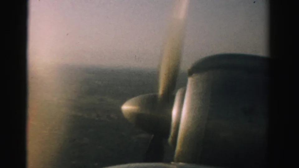 1957 Nevada aerial home-movie view with the small plane propeller and engine visible at the edge of frame.