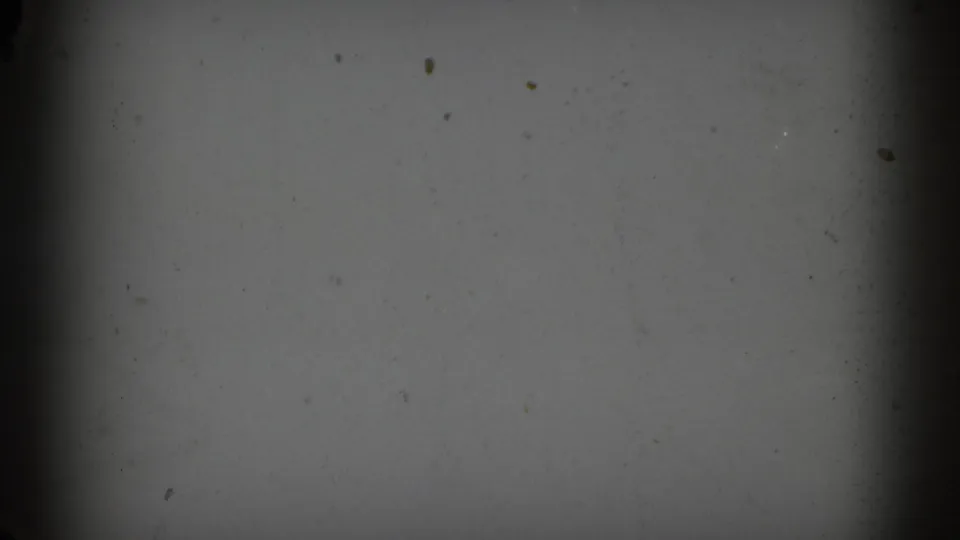 Opening frame shows a largely blank gray film area with dark vertical edge shadow and visible dust on the 8mm scan.