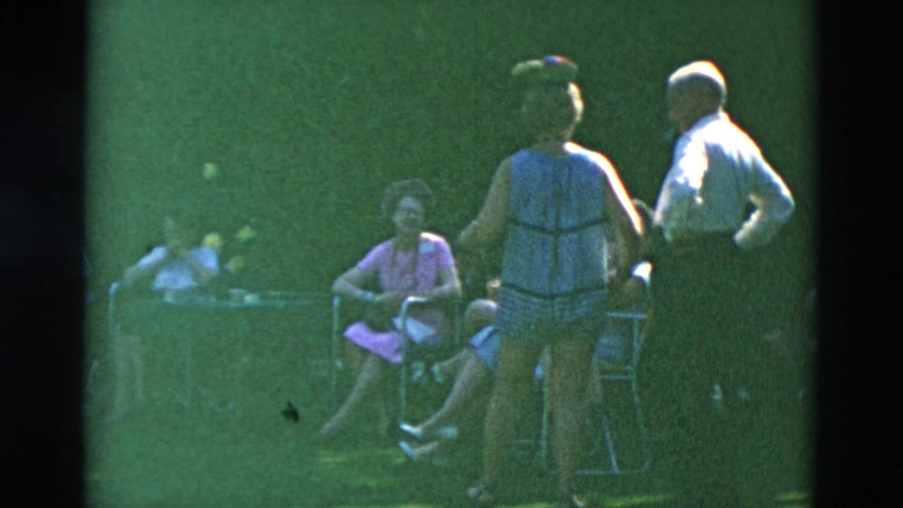 A woman and man stand near seated adults in lawn chairs.