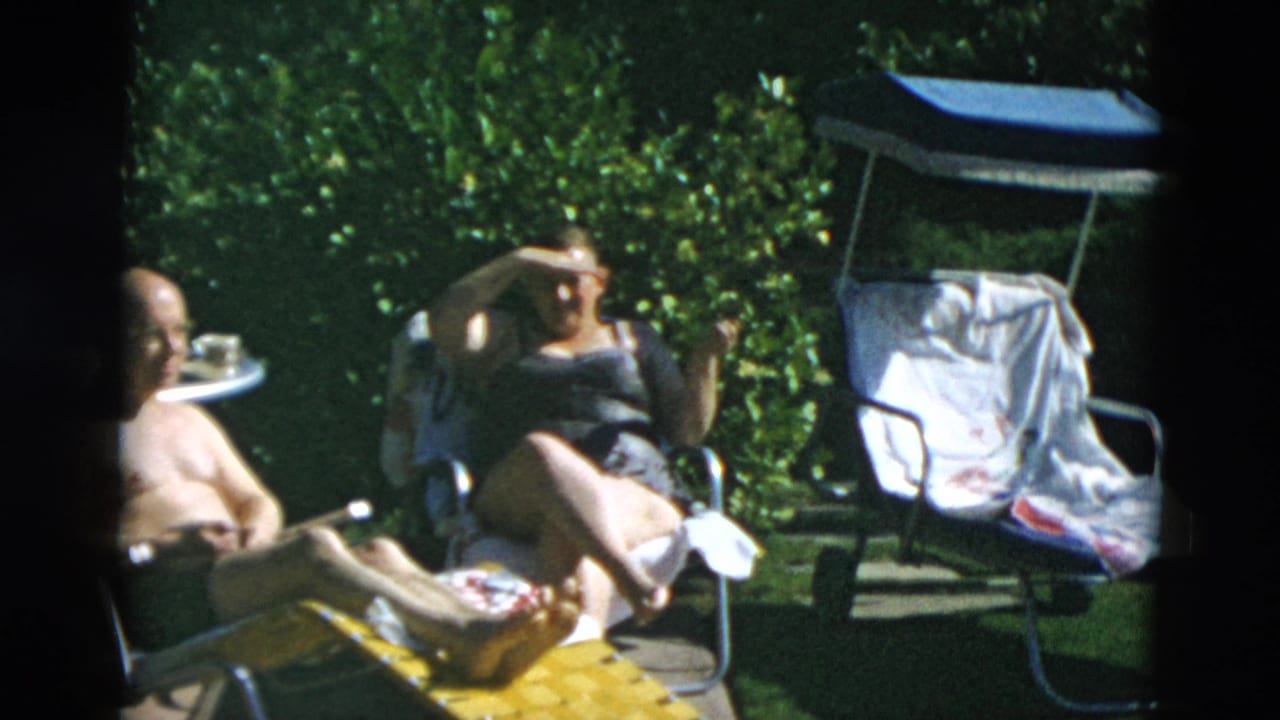 Adults reclining in lawn chairs in a sunny backyard garden.