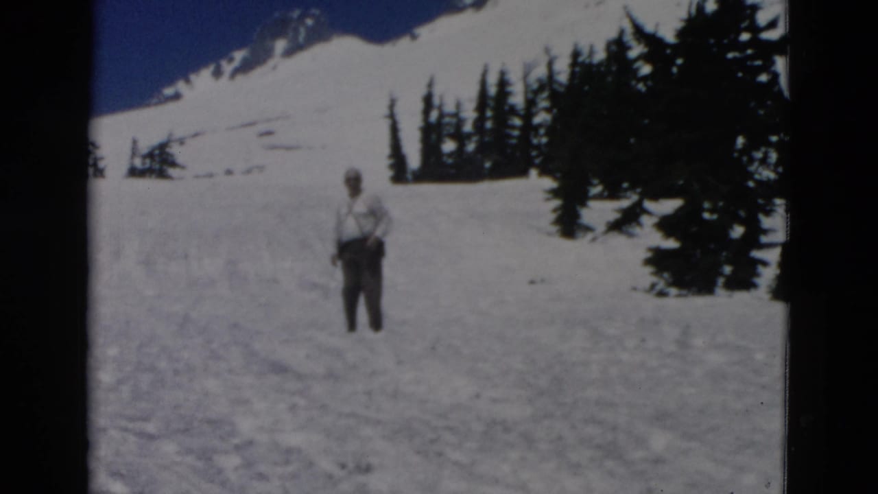 Man facing the camera while standing in snow with trees behind him.