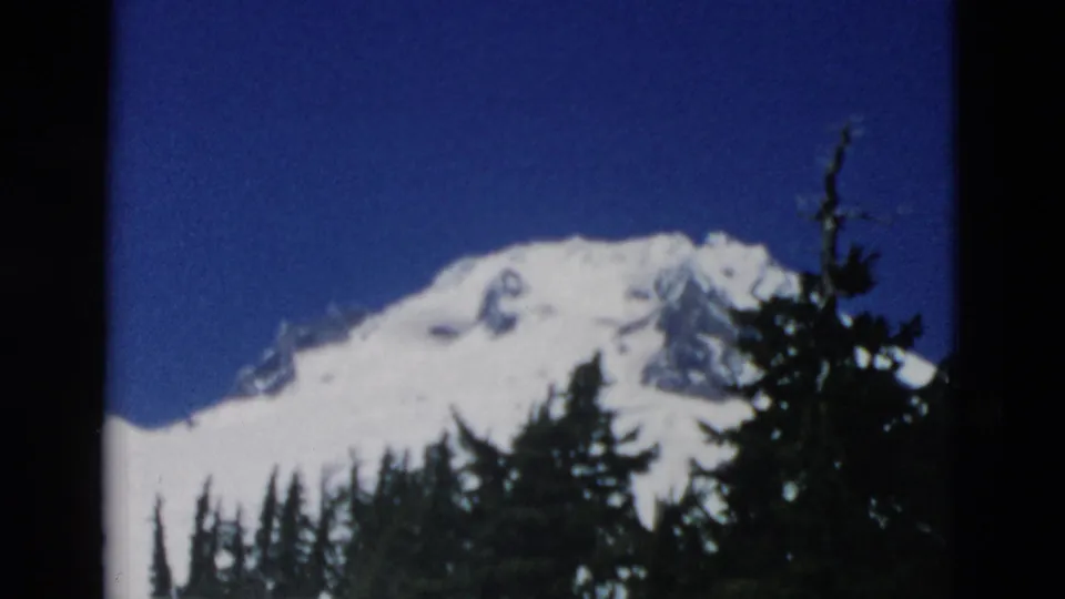 The final frame centers on the snowy mountain and tree line, with no clear person visible in this sampled still.