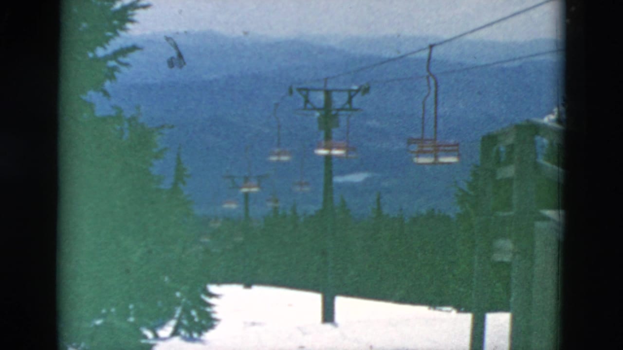 A snowy mountain ski-lift line appears above dark evergreens, with empty chairs, lift towers, and blue ridges in the background.