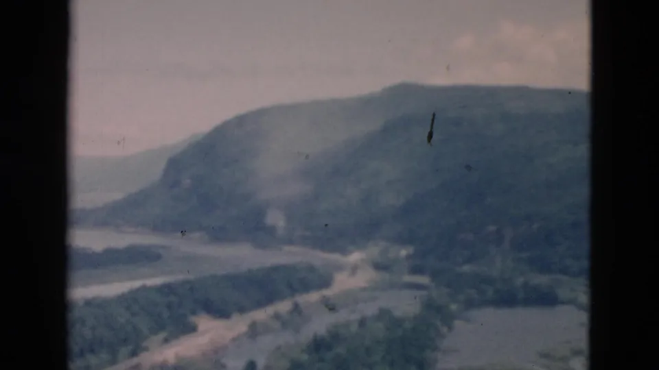 Home-movie frame with dark gate borders around a soft view of mountains, water, and wooded shoreline.