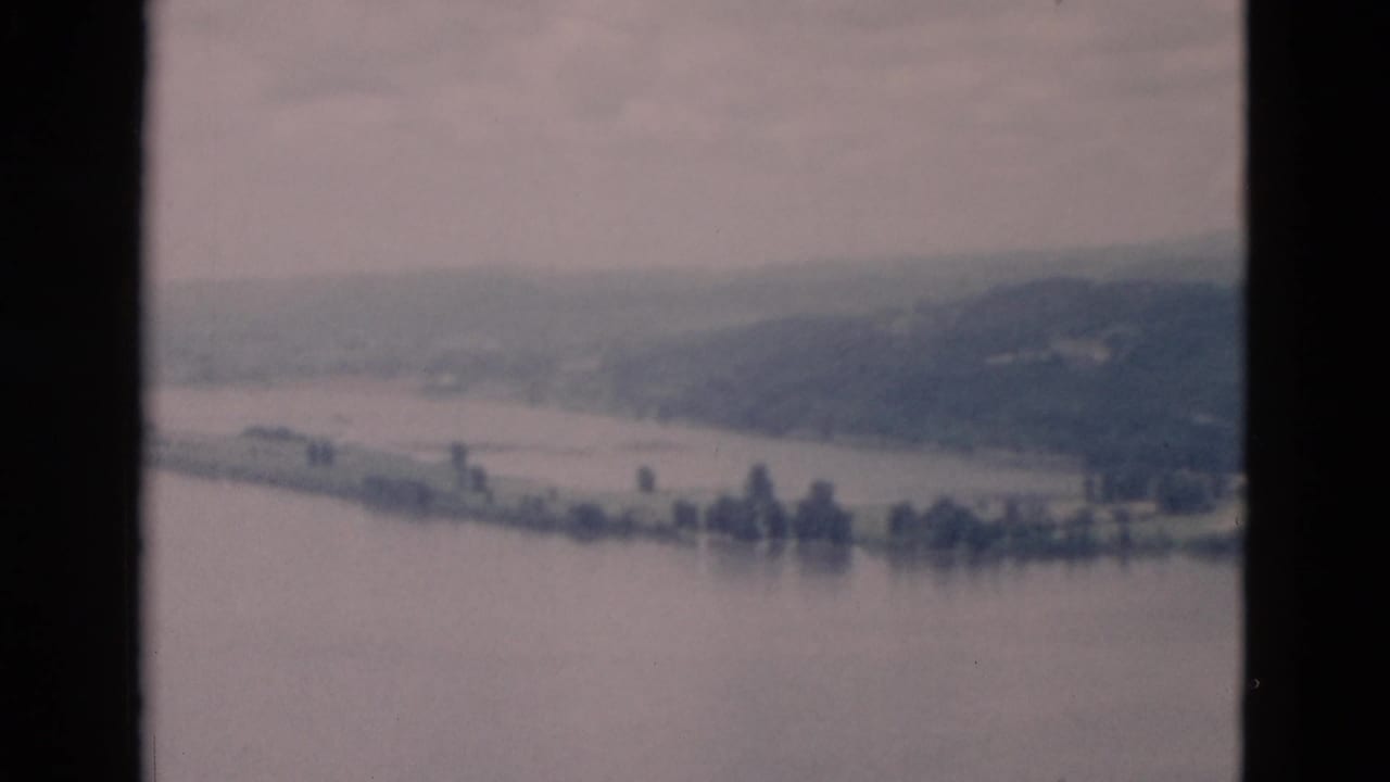 The lake fills the foreground while a pale shoreline, small tree clusters, and low hills sit in the distance.