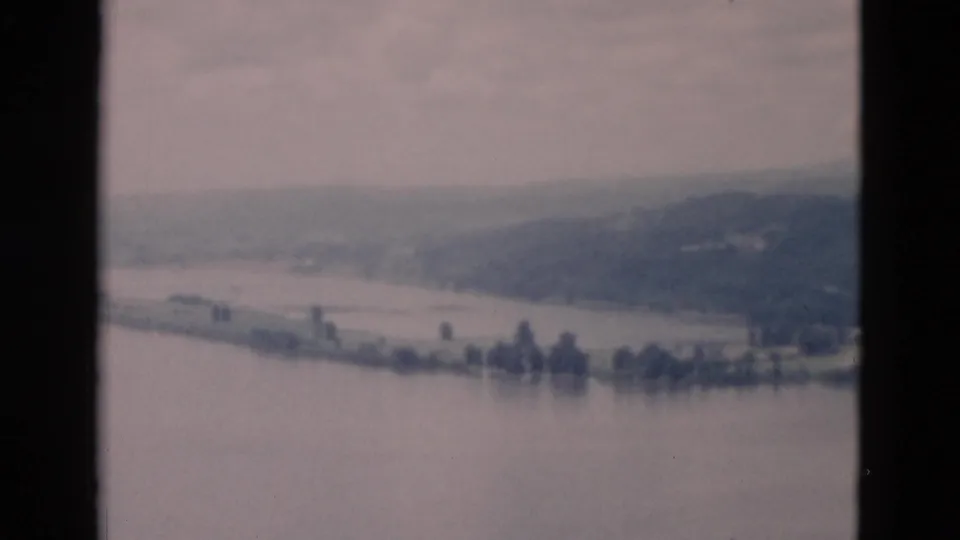The lake fills the foreground while a pale shoreline, small tree clusters, and low hills sit in the distance.