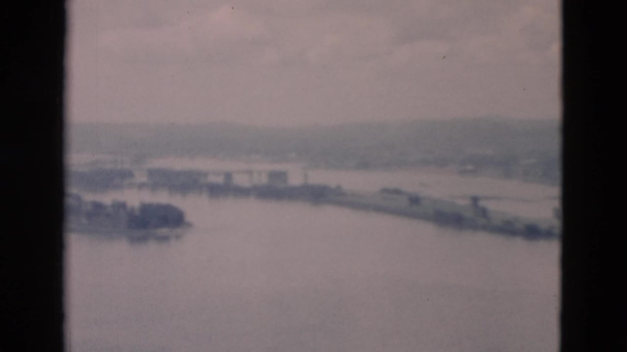 Soft 8mm view of a wide river with a narrow island and distant shoreline.