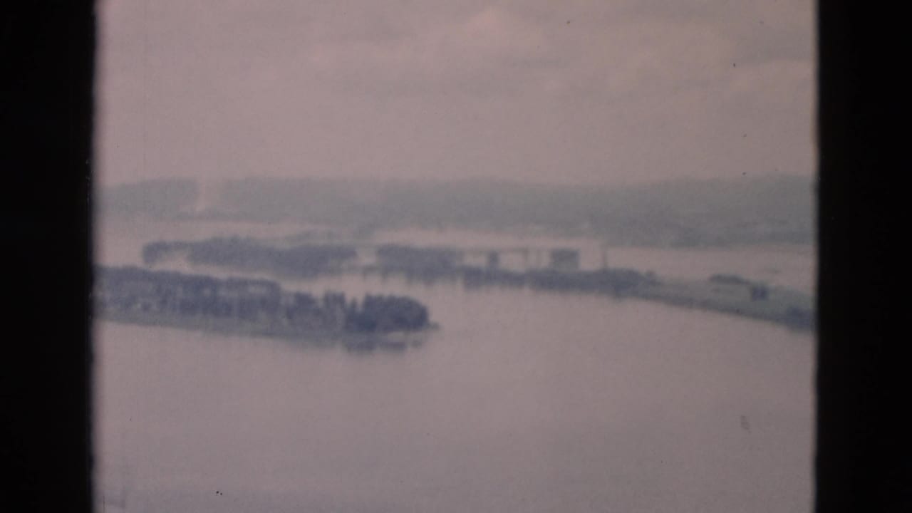 River panorama with island, far bank, and dark vertical film border.