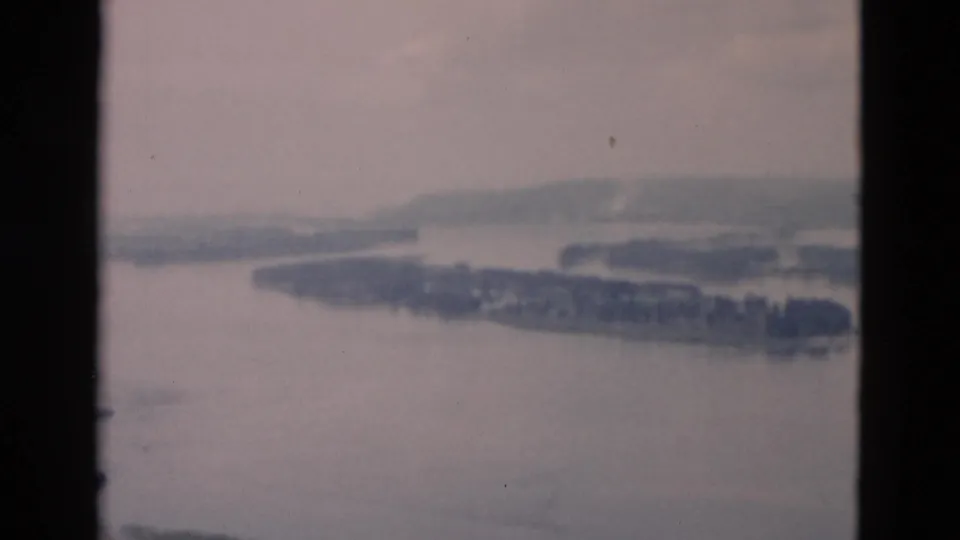 A muted 8mm landscape frame shows a river or bay with wooded islands, pale sky, and low hills in the distance.