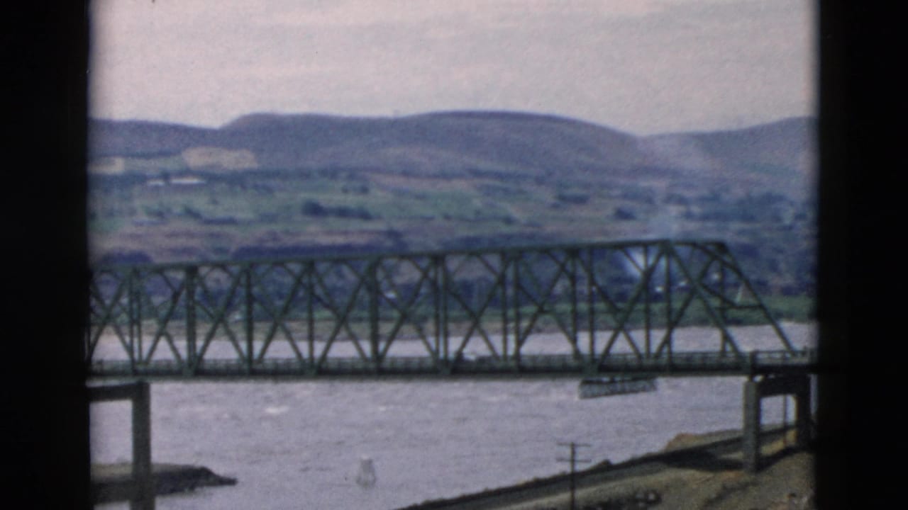 River bridge and low mountains seen through a dark window-like border.
