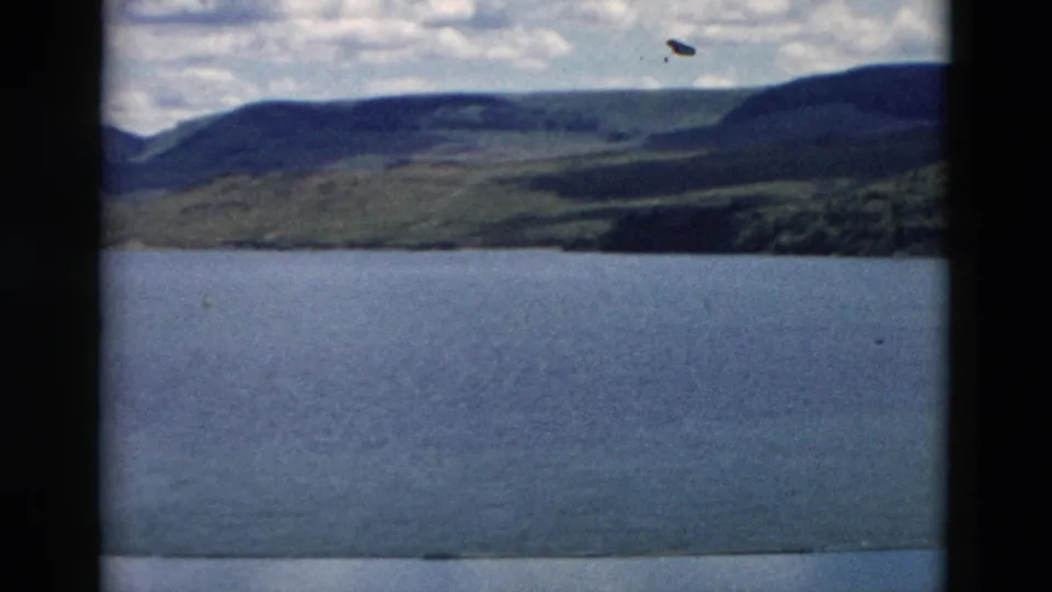 1958 Montana 8mm frame of lake water, distant shoreline, and a broad dark ridge in a handheld scenic pan.