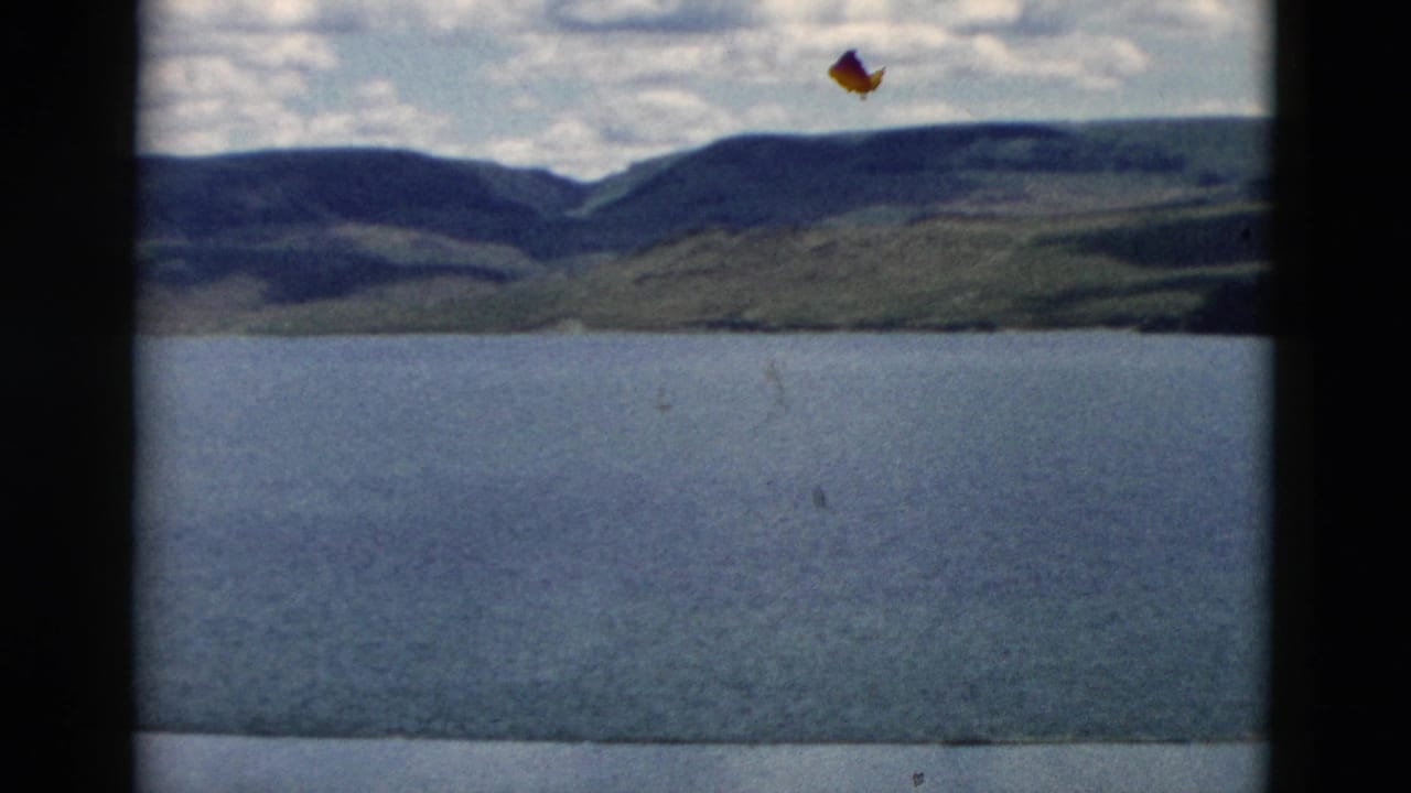 Lake water with distant hills and mountains under a partly cloudy sky.