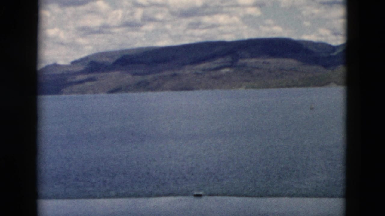 Wide water view with a distant hilly shoreline and cloudy sky.
