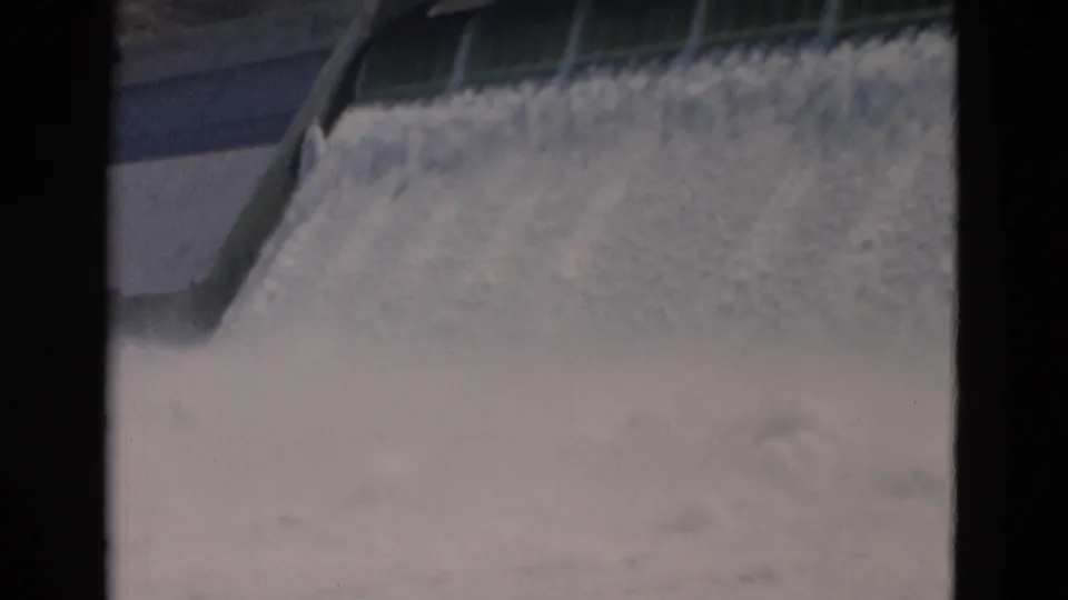 1958 Montana 8mm frame emphasizing the foaming cascade below the dam, with the concrete side wall partly visible.