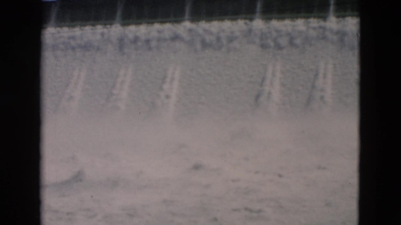 Water spills down a concrete dam face, creating pale mist and soft spray.