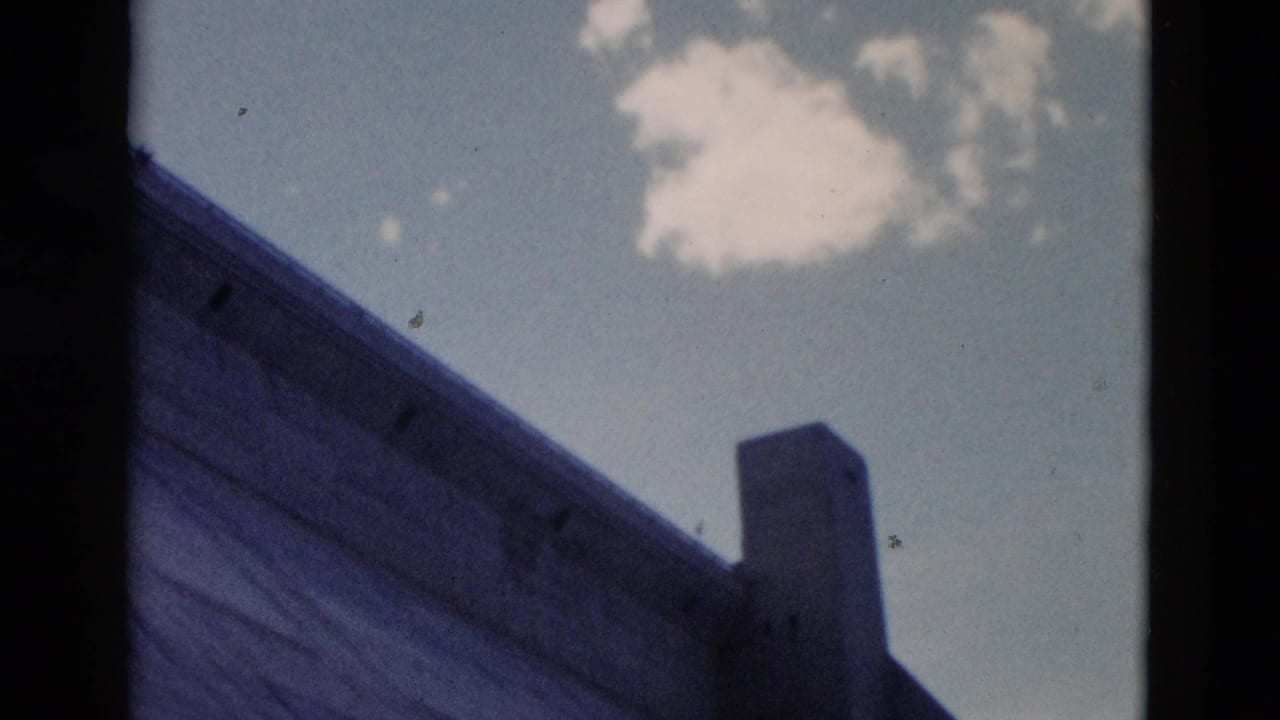 Low-angle view of a sloped concrete or masonry edge, vertical pillar, blue sky, and white cloud.