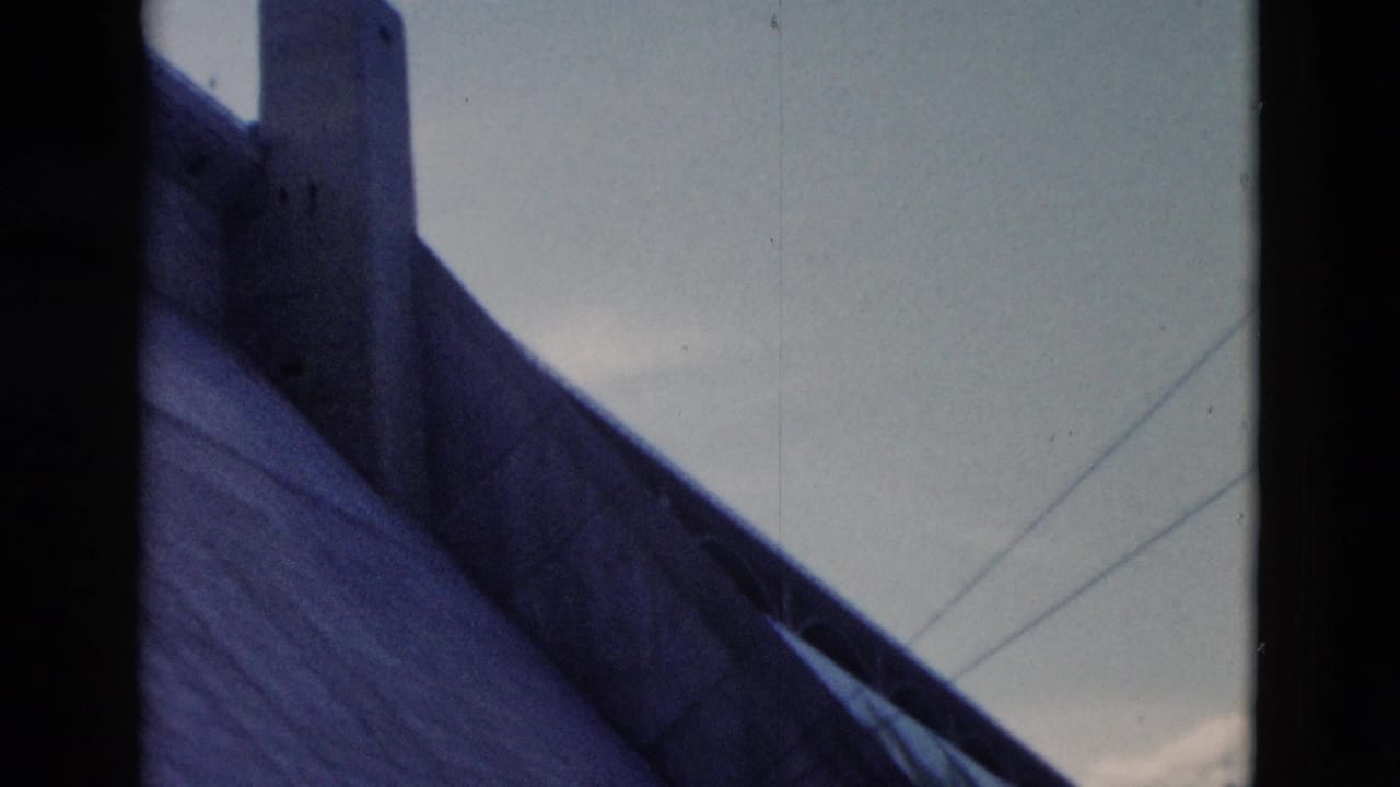 Steep dark roof and chimney beneath a pale sky.