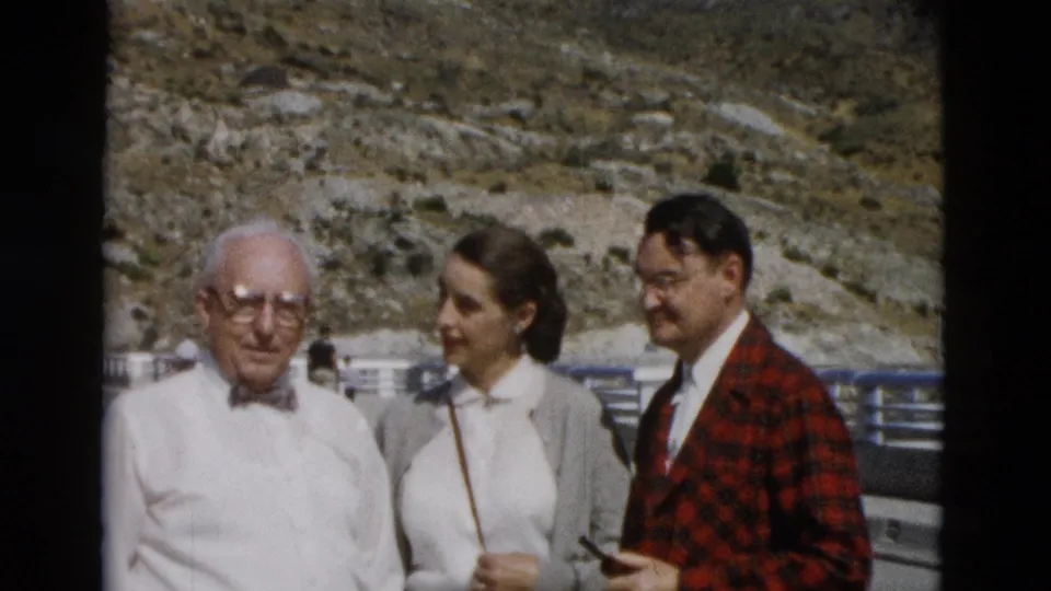 A family group at a Montana roadside overlook, with an older man facing camera and two adults standing beside him in bright sunlight.