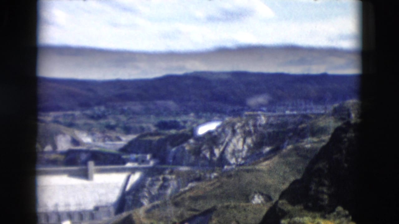 Dam and canyon landscape viewed through dark film-frame borders.