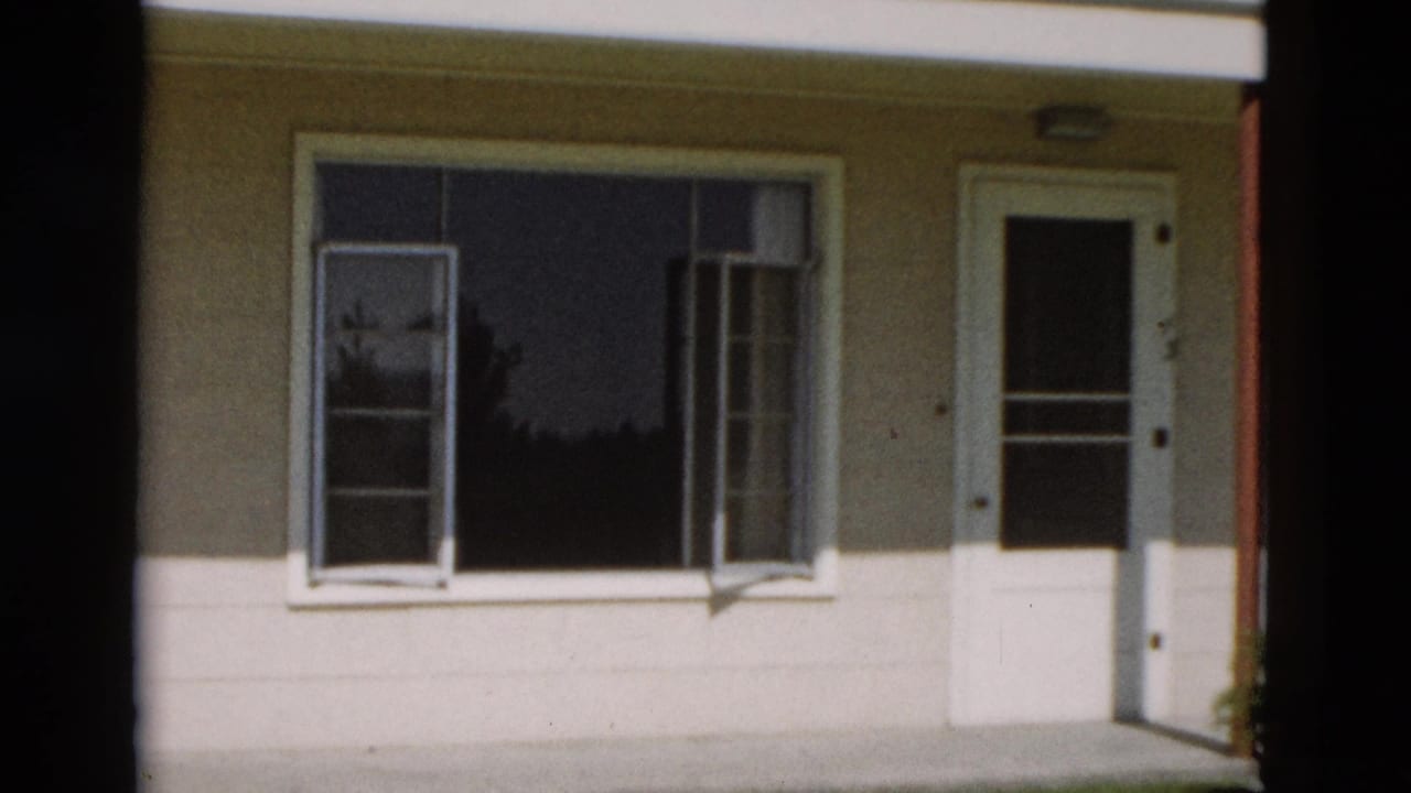 1958 Yellowstone, Wyoming home-movie frame showing a modest house facade with open window sashes and a white screen door.