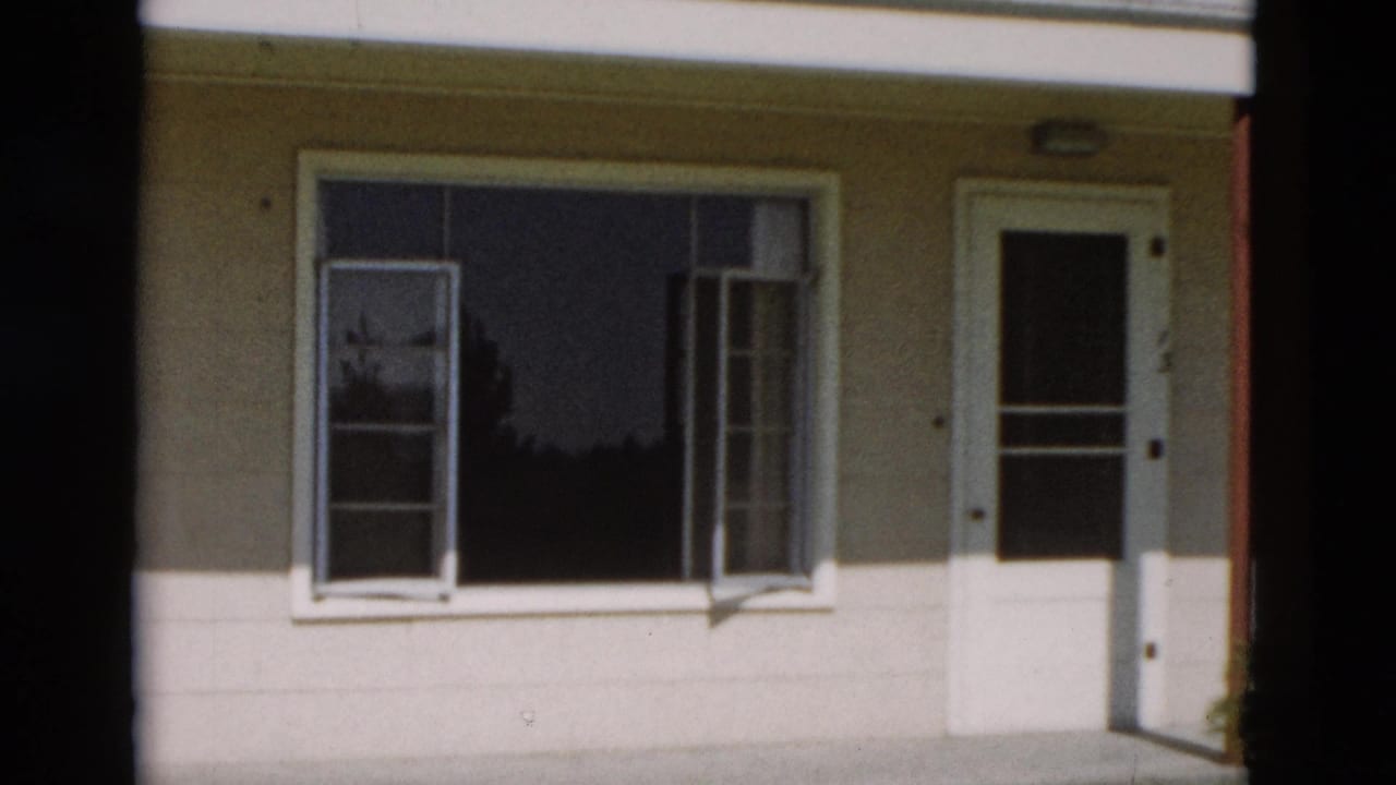 House facade with a large window, open side sashes, and a white door.
