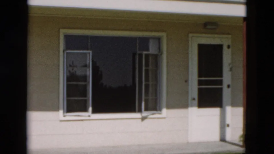 1958 Yellowstone, Wyoming home-movie frame showing the same modest exterior with siding, window, and screen door.