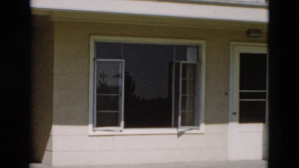 1958 Yellowstone, Wyoming frame of a modest residential facade with open window sashes and a partially edge-framed door.