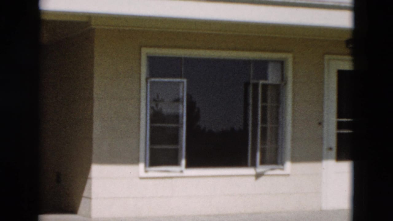 1958 Yellowstone 8mm frame with open window panes, white trim, dark glass, and a vertical film-frame border across the view.