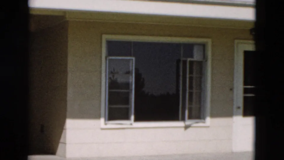 1958 Yellowstone 8mm frame with open window panes, white trim, dark glass, and a vertical film-frame border across the view.