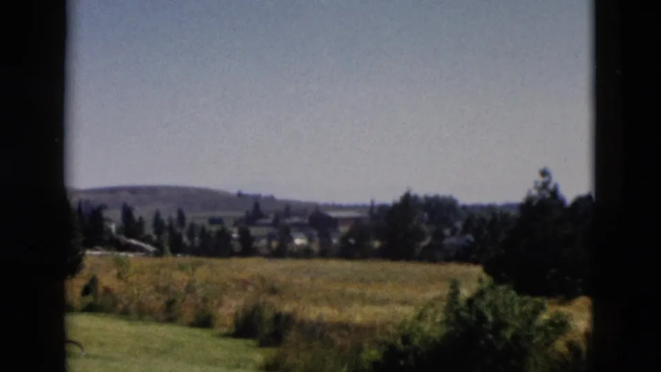 1958 Yellowstone-area window view of grassland, shrubs, trees, and low hills in soft 8mm color.